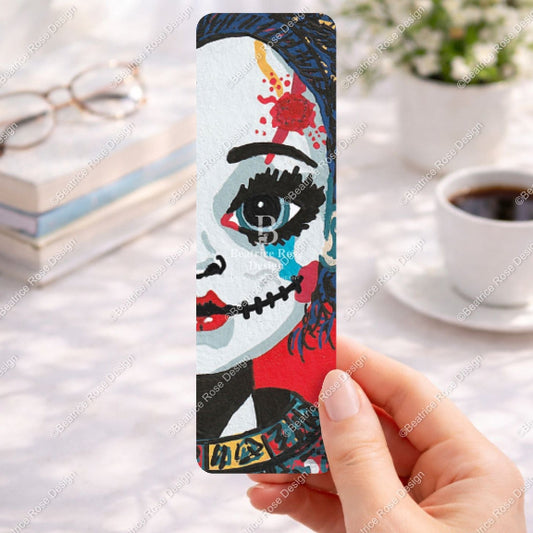 Bookmark with artistic design held by a hand on a desk with coffee and books.