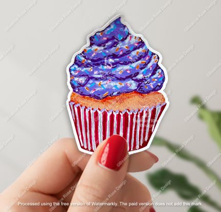 Sticker of a cupcake with purple frosting held by a hand against a light gray background