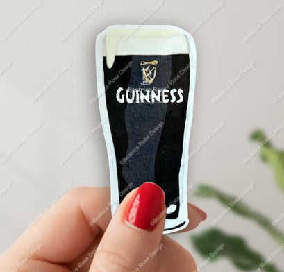 Hand holding a Guinness-themed pint glass with a blurred background